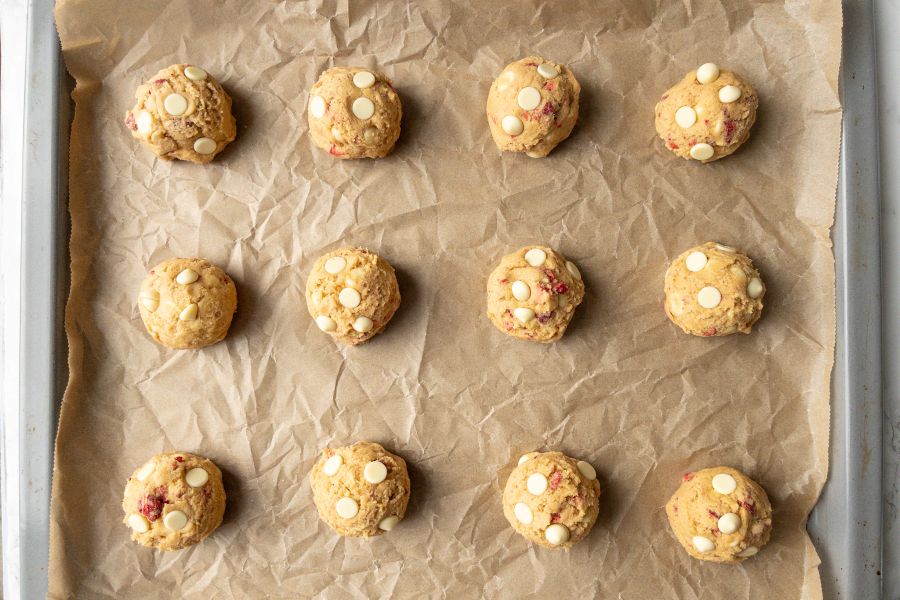 12 Erdbeer Cookies mit weißer Schokolade auf dem Blech vor dem Backen